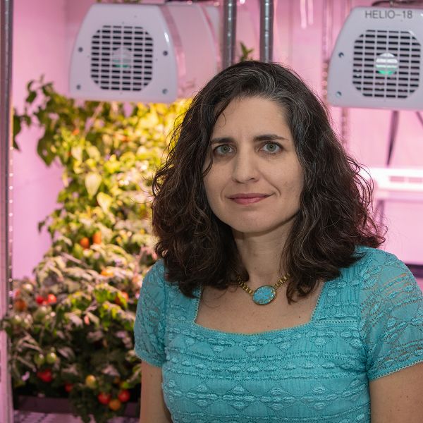Gioia Massa, a NASA scientist, is poses inside a lab with plants.